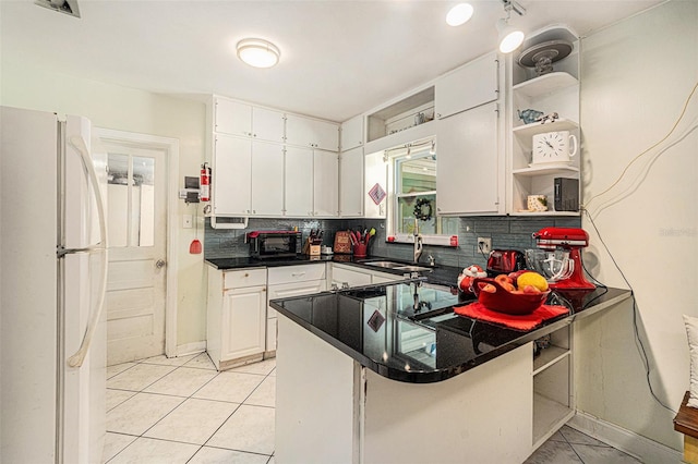 kitchen featuring open shelves, a peninsula, freestanding refrigerator, decorative backsplash, and white cabinetry