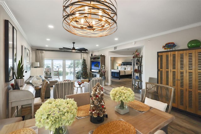 dining area with wood-type flooring, ceiling fan with notable chandelier, and ornamental molding