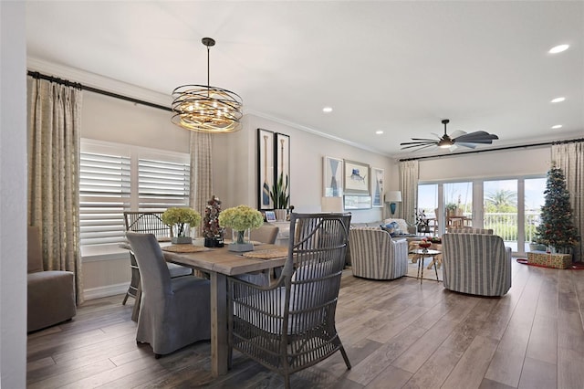 dining room featuring ceiling fan with notable chandelier, crown molding, and dark wood-type flooring