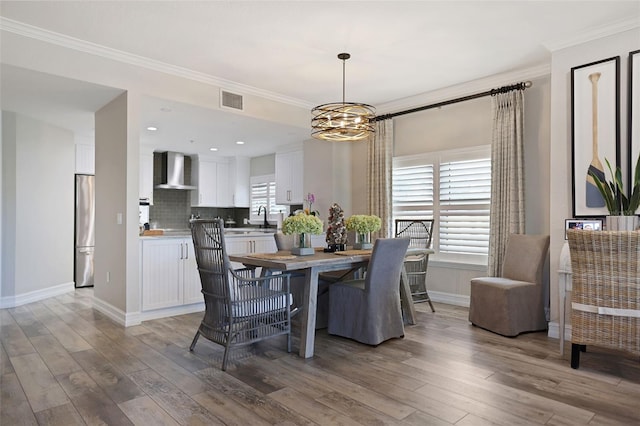 dining room with a notable chandelier, wood-type flooring, and ornamental molding