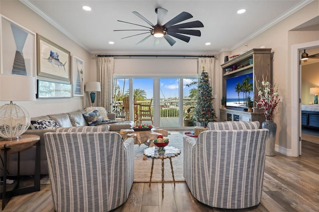 living room with hardwood / wood-style flooring, ceiling fan, and crown molding