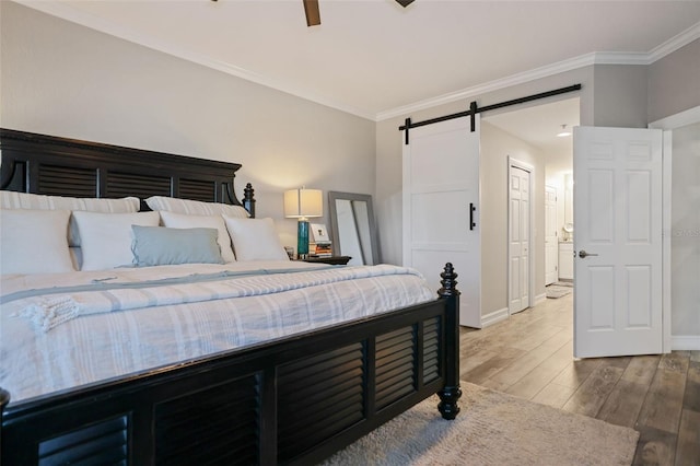 bedroom with crown molding, hardwood / wood-style flooring, ceiling fan, a barn door, and a closet