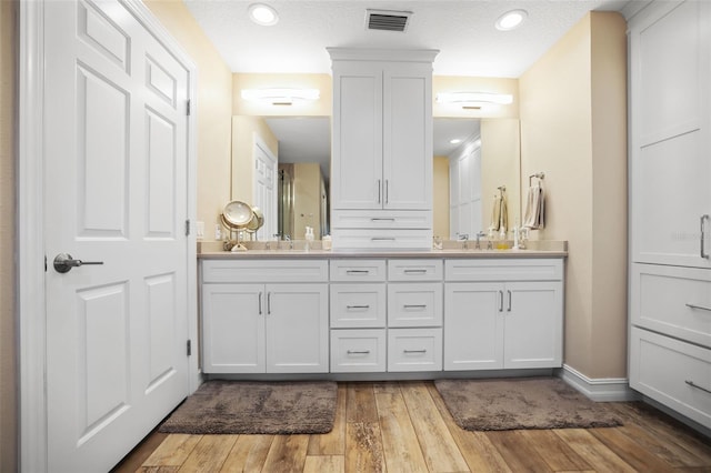 bathroom featuring wood-type flooring, vanity, and a textured ceiling