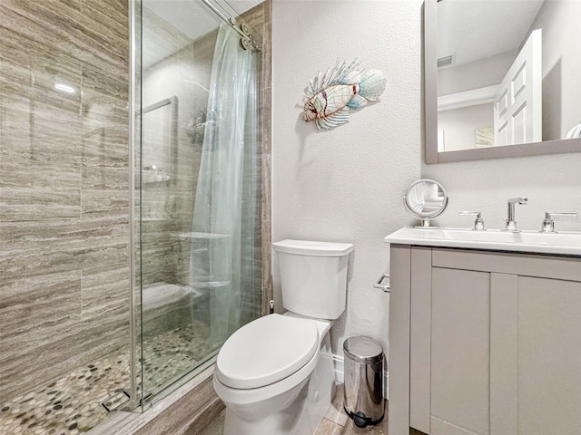 bathroom with tiled shower, vanity, and toilet