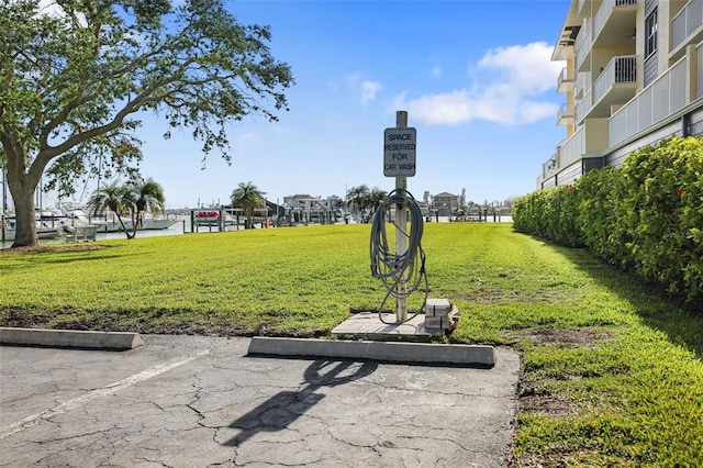 surrounding community with a water view and a yard