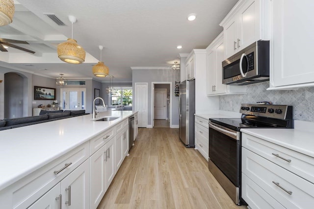 kitchen with appliances with stainless steel finishes, coffered ceiling, sink, white cabinetry, and hanging light fixtures