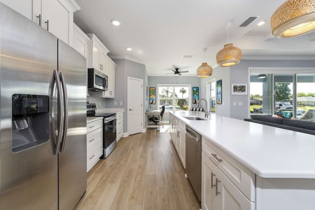 kitchen with stainless steel appliances, ceiling fan, sink, pendant lighting, and white cabinets