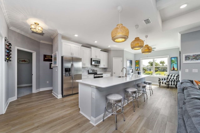 kitchen featuring white cabinetry, sink, pendant lighting, a breakfast bar, and appliances with stainless steel finishes