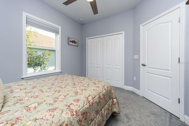 carpeted bedroom with ceiling fan, a closet, a textured ceiling, and multiple windows