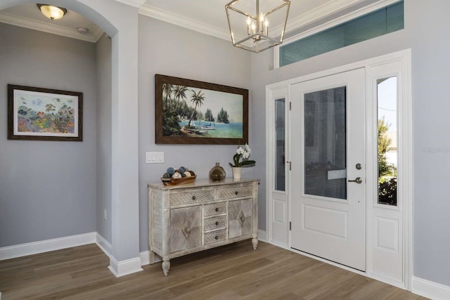 entrance foyer with a chandelier, a healthy amount of sunlight, dark hardwood / wood-style flooring, and ornamental molding