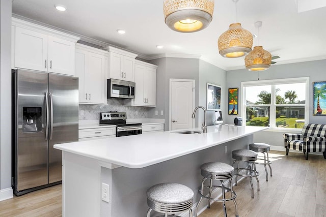 kitchen with a kitchen island with sink, sink, white cabinets, and appliances with stainless steel finishes