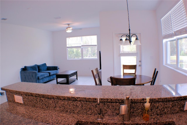 tiled dining room with ceiling fan with notable chandelier