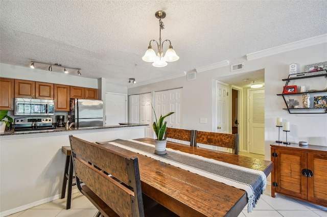 tiled dining area with crown molding, a textured ceiling, and an inviting chandelier