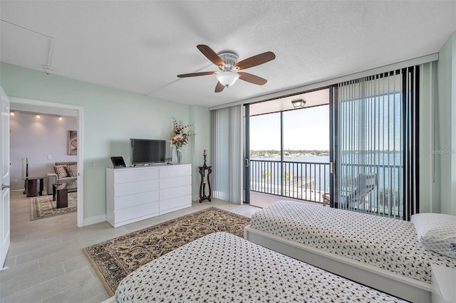 bedroom with access to outside, ceiling fan, a textured ceiling, and a wall of windows