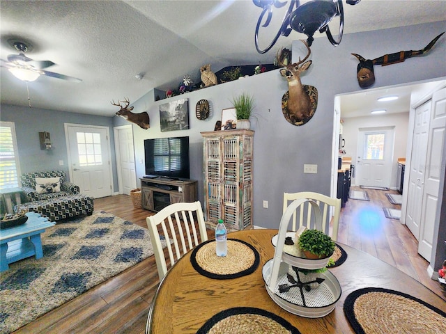 dining area with a textured ceiling, a wealth of natural light, lofted ceiling, and hardwood / wood-style flooring