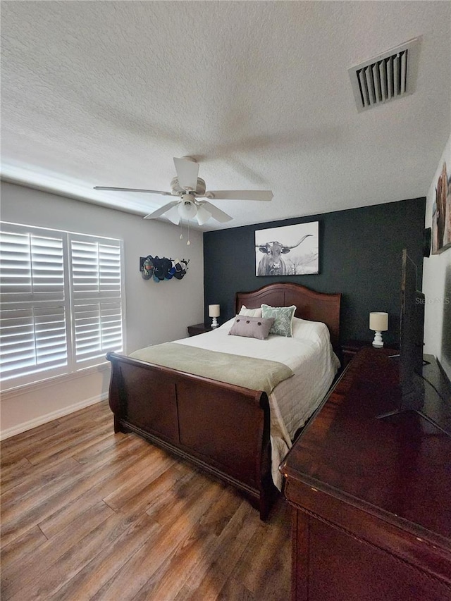 bedroom featuring ceiling fan, a textured ceiling, and hardwood / wood-style flooring