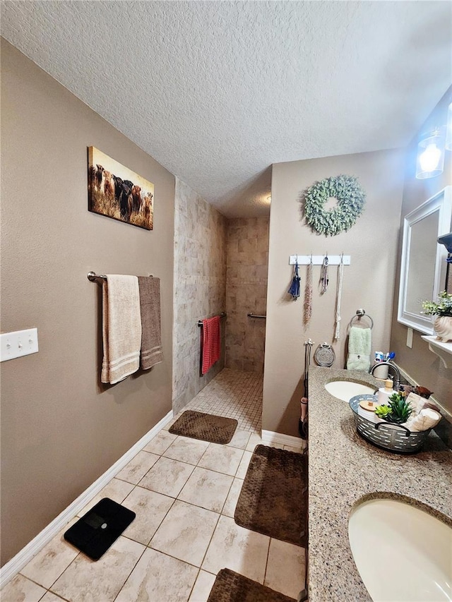 bathroom with a tile shower, tile patterned flooring, vanity, and a textured ceiling