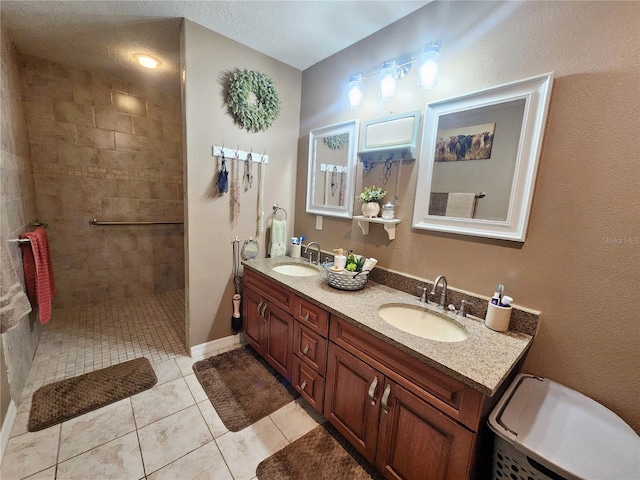 bathroom featuring tile patterned flooring, vanity, tiled shower, and a textured ceiling