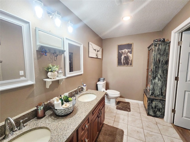 bathroom featuring tile patterned floors, vanity, a textured ceiling, and toilet