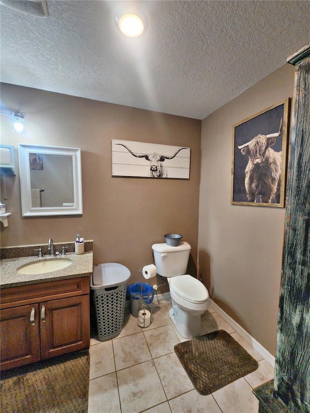 bathroom featuring tile patterned flooring, vanity, toilet, and a textured ceiling