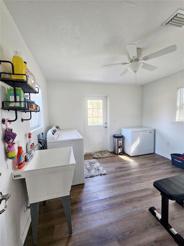 laundry area featuring a textured ceiling, ceiling fan, washer and clothes dryer, sink, and hardwood / wood-style floors