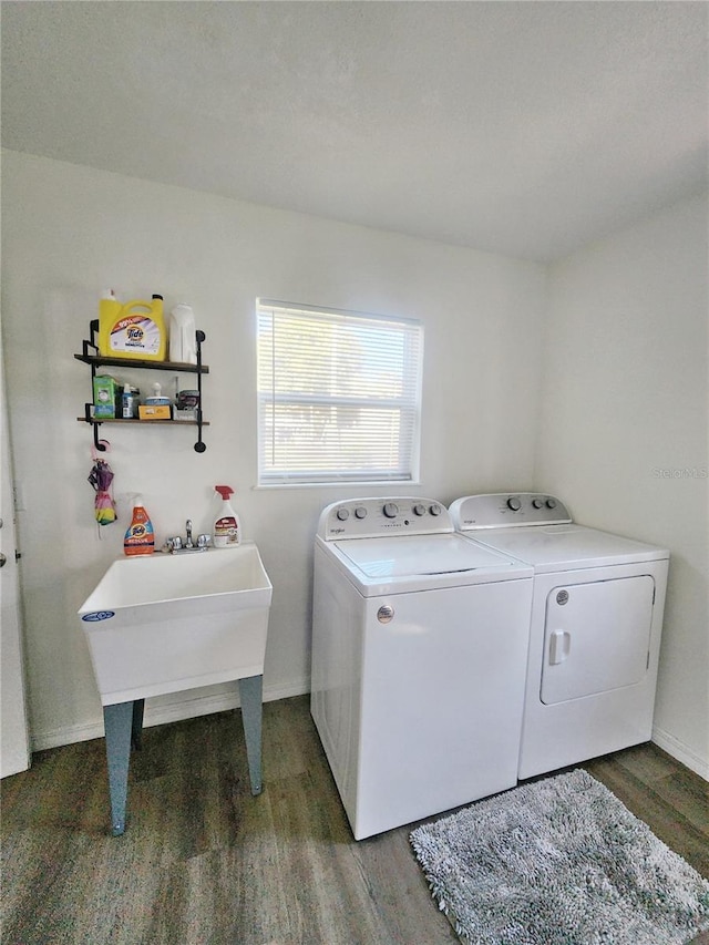 clothes washing area with washing machine and clothes dryer and dark hardwood / wood-style flooring