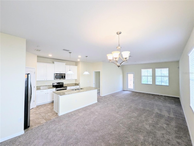 kitchen with a center island with sink, white cabinets, sink, decorative light fixtures, and stainless steel appliances