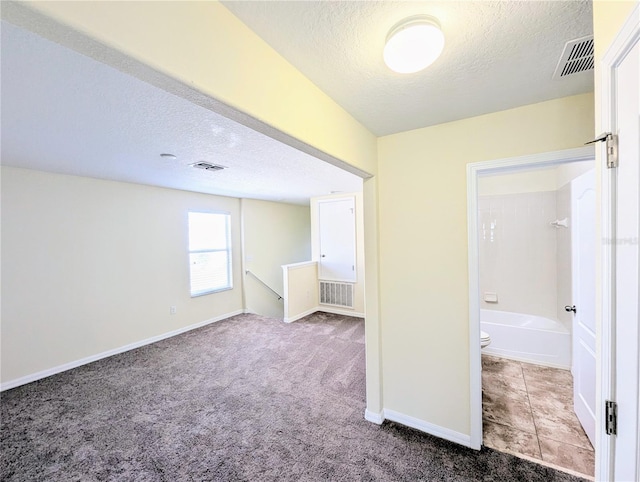 interior space with carpet, a textured ceiling, and ensuite bathroom