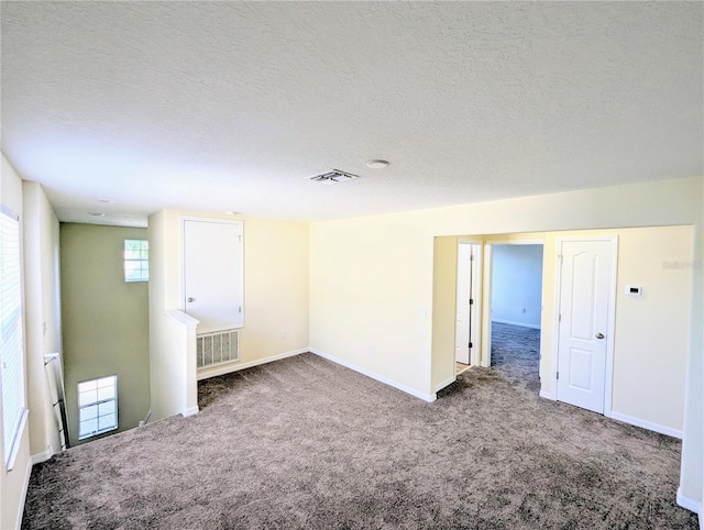 carpeted empty room featuring a textured ceiling