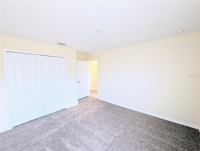 unfurnished bedroom featuring a closet and light colored carpet