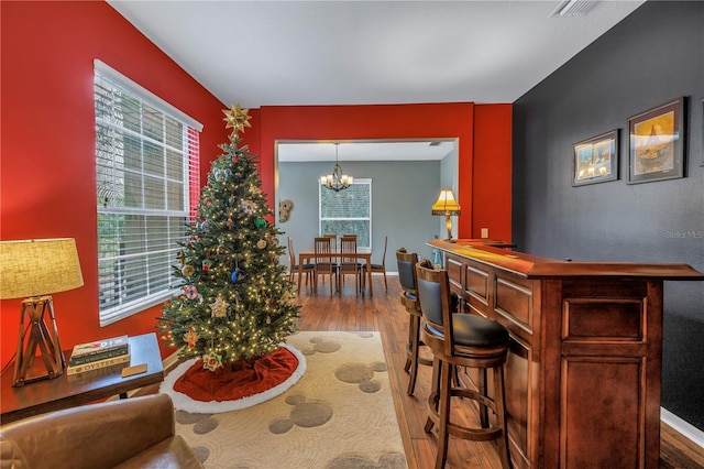 interior space with a chandelier, indoor bar, and light hardwood / wood-style flooring