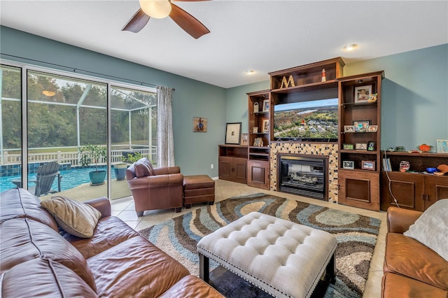 tiled living room with a tile fireplace and ceiling fan