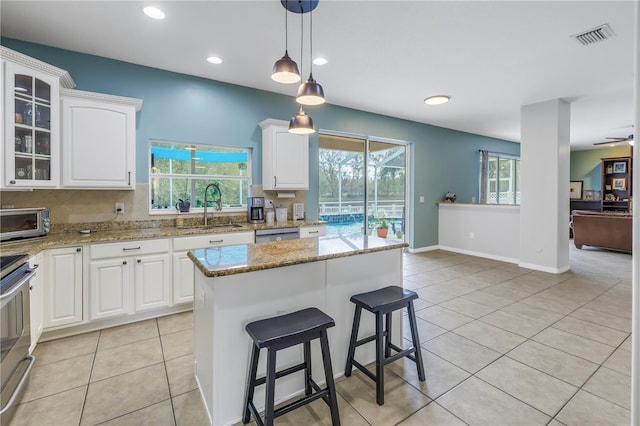 kitchen with white cabinets, a kitchen island, sink, and a wealth of natural light