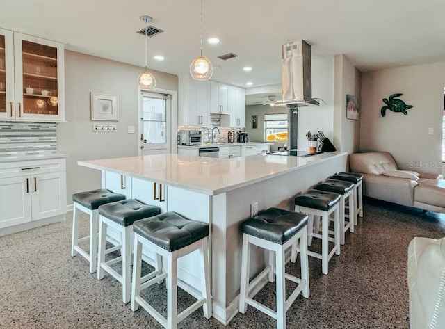 kitchen with island exhaust hood, decorative backsplash, white cabinetry, and a healthy amount of sunlight