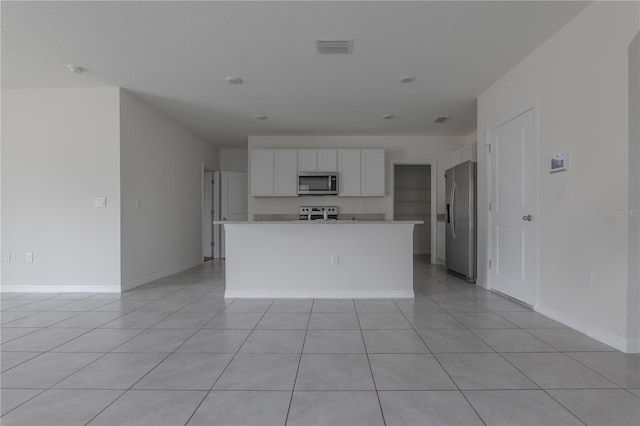 kitchen with a kitchen island, white cabinets, light tile patterned flooring, and appliances with stainless steel finishes