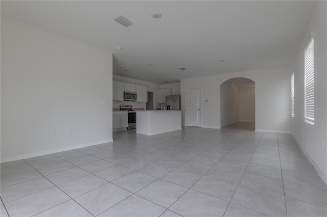 unfurnished living room with light tile patterned flooring and plenty of natural light