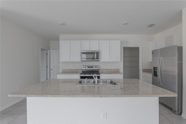 kitchen with stainless steel appliances, a center island with sink, light tile patterned floors, white cabinets, and sink