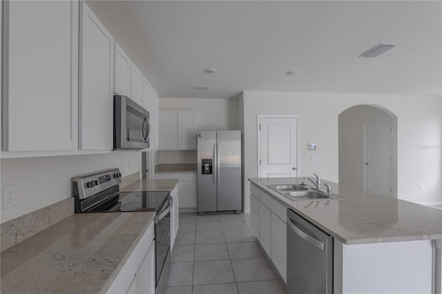 kitchen featuring a center island with sink, light tile patterned floors, white cabinetry, appliances with stainless steel finishes, and sink