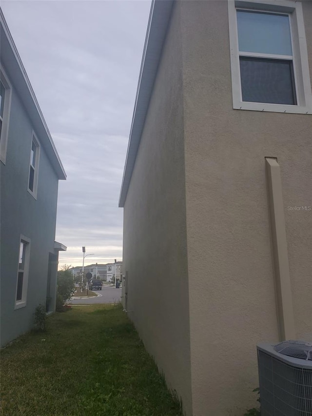 view of side of home with cooling unit and a lawn