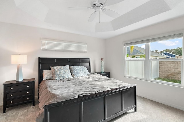 carpeted bedroom with ceiling fan and a raised ceiling