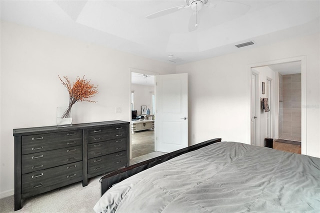 carpeted bedroom with a raised ceiling, ceiling fan, and ensuite bathroom