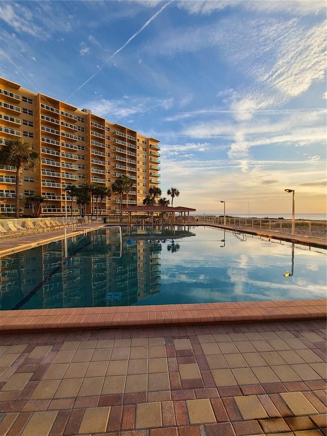 pool at dusk featuring a water view