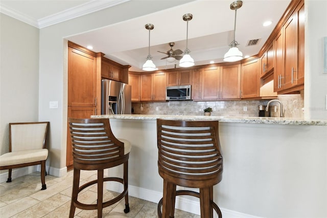 kitchen featuring light stone countertops, appliances with stainless steel finishes, a breakfast bar, and decorative backsplash