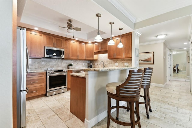 kitchen with pendant lighting, appliances with stainless steel finishes, a kitchen breakfast bar, light stone counters, and decorative backsplash