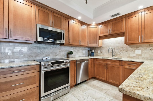 kitchen featuring light stone counters, sink, decorative backsplash, and stainless steel appliances