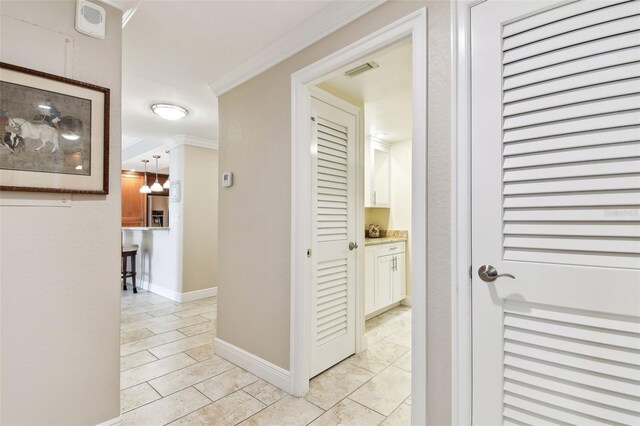 hallway featuring crown molding and light tile patterned floors