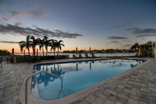 pool at dusk with a patio area