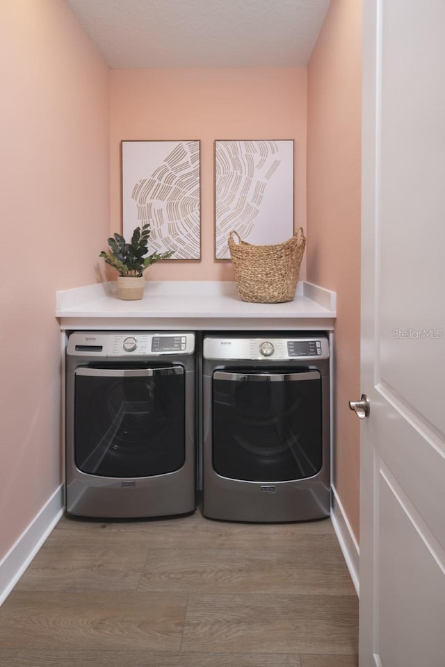 17390 Moonflower Dr Unit 202, Venice, FL 34293 - clothes washing area featuring washer and dryer, laundry area, wood finished floors, and baseboards