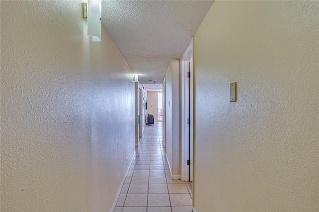 hall featuring light tile patterned floors and a textured ceiling