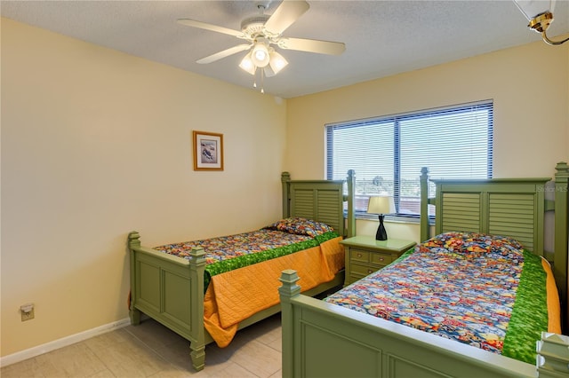 bedroom featuring ceiling fan, light tile patterned floors, and a textured ceiling